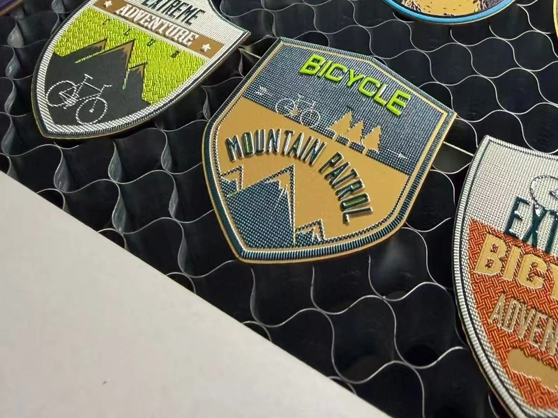 Raised UV-printed transfer badges with an embroidery-like texture on the honeycomb table of a KASU laser cutter
